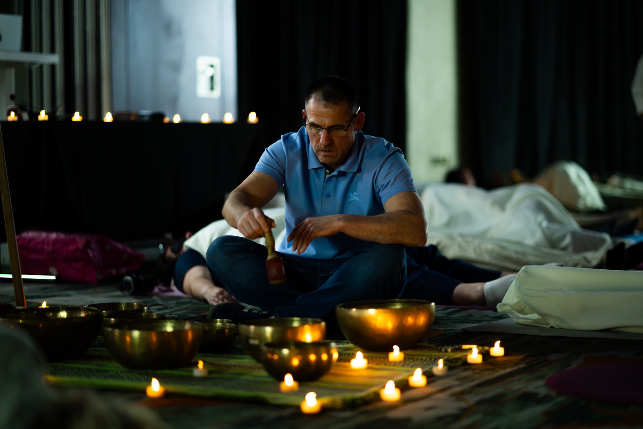 Scottish Gongsta playing singing bowls surrounded by candlelight at KOMO Immersion