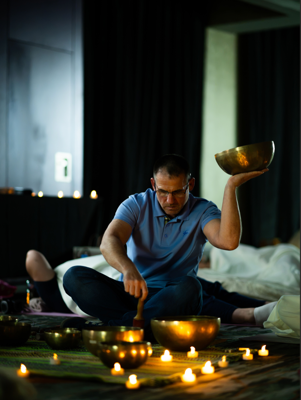 Scottish Gongsta holding a singing bowl aloft during a candlelit sound bath